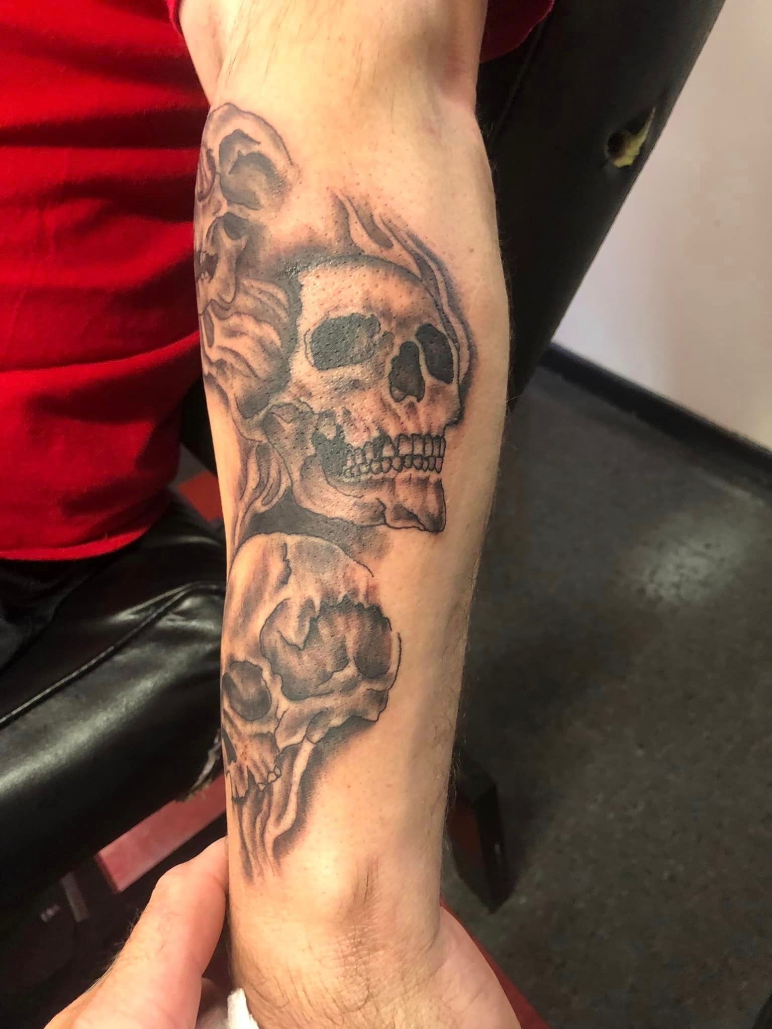 Three skulls arm tattoo